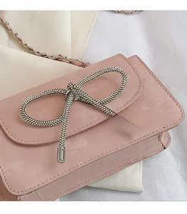 Detail der hellrosa Wildledertasche mit großer silberner Strass-Schleife und Kettenriemen