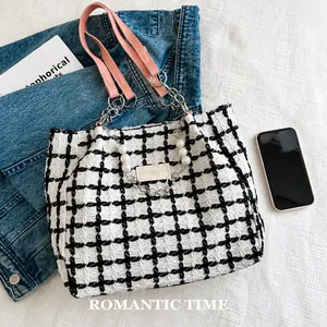 Close-up of checkered tweed tote bag with pink leather strap and decorative pearl chain