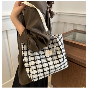 Detail of tweed checkered tote bag with pearl chain decoration and leather shoulder strap