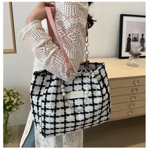 Detail of plaid tote bag featuring pink leather strap, silver chain and pearl pendant charm