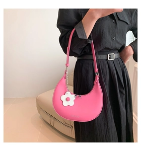 Dettaglio borsa hobo rosa a mezzaluna con texture in pelle e ciondolo a fiore