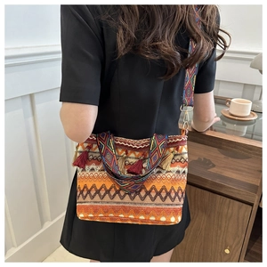 Dettaglio di borsa etnica intrecciata con nappe e tracolla in tessuto jacquard colorato