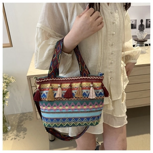 Dettaglio della borsa bohémien intrecciata con motivi geometrici e lunghe nappe colorate