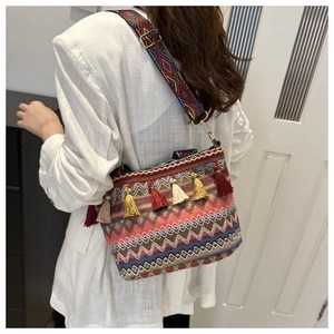 Dettaglio borsa tessuta boho con motivi etnici e nappe a frangia colorate decorative