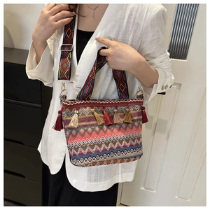 Dettaglio macro della borsa tote boho intrecciata con nappe colorate e tracolla