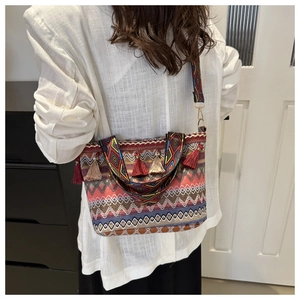 Dettaglio della borsa bohémien intrecciata con motivi geometrici colorati e nappe decorative