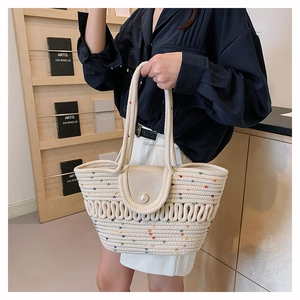 Close-up of woven tote bag with colorful embroidery and a pearl buckle closure