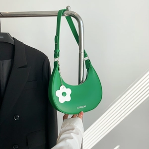 Borsa hobo a mezzaluna verde con ciondolo a fiore esposta su un supporto metallico