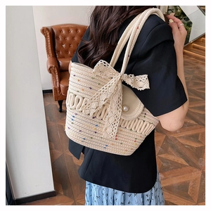 Detailed view of straw handbag with colorful embroidery and elegant white lace bow decoration