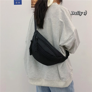 Detalle de la riñonera minimalista de lona negra llevada por una modelo en sudadera
