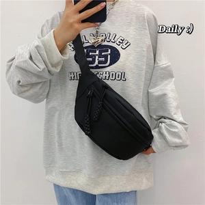 Bolso de pecho minimalista en lona negra con tirador trenzado mostrado puesto al cuerpo