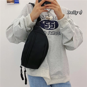 Foto de uso de un bolso riñonera de nailon negro combinado con una sudadera gris casual