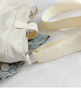 Detail of silver metal buckle and thick woven strap on large cream tote bag