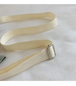 Detail of adjustable off-white woven shoulder strap with shiny silver metal buckle