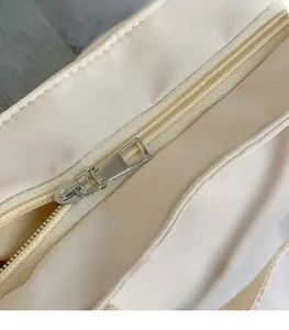 Detailed close-up showing the smooth silver metal zipper puller on a beige canvas bag