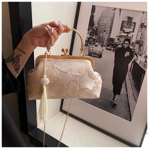 Close-up of floral embroidery on beige vintage clutch bag with gold heart clasp