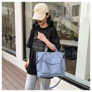 Detail view of light blue nylon tote bag with metal buckles and adjustable strap