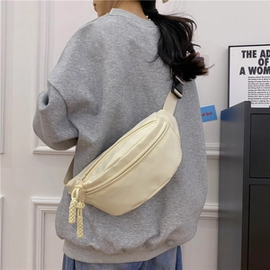 Primer plano de riñonera de lona beige con tela texturizada y detalles de hebilla negra