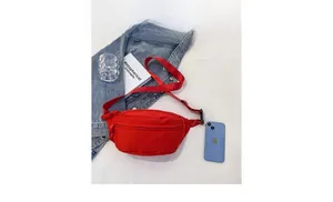 Comparación detallada del tamaño del bolso bandolera de lona roja con un teléfono
