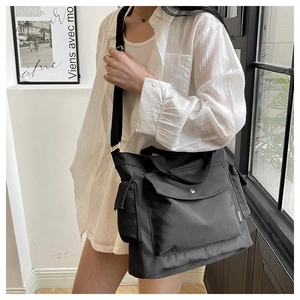 Detail of black multi-pocket canvas bag with fashion label and adjustable shoulder strap