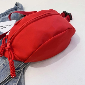 Detalle de riñonera de nailon rojo con tirador tejido y correa ajustable