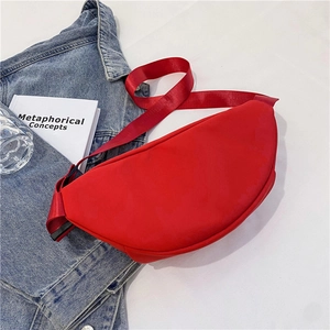 Primer plano de un bolso de nylon rojo con correa ancha sobre una chaqueta denim