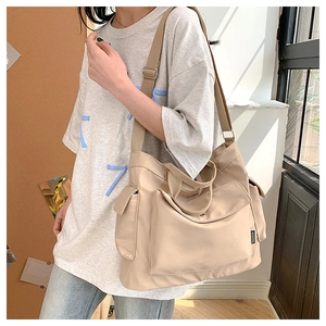 Detail of adjustable shoulder strap and side utility pocket on beige tote bag