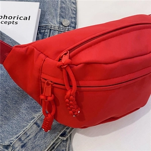 Detalle de la riñonera de nailon roja con múltiples bolsillos y tiradores trenzados