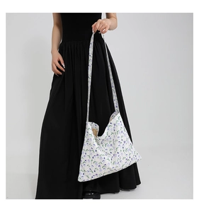 Dettaglio della borsa tote in tela bianca con fiori viola su modella con abito nero