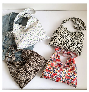 Flat lay of canvas tote bags in leopard print and floral patterns with casual props