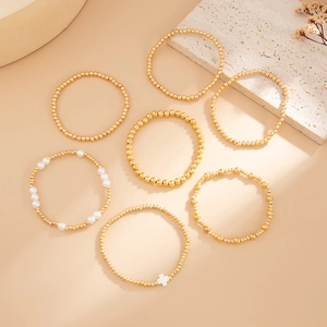 Détail d'un ensemble de sept bracelets élastiques dorés avec perles et croix