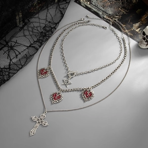 Dettaglio di collana gotica multistrato con croce d'argento, cuori rossi e stella