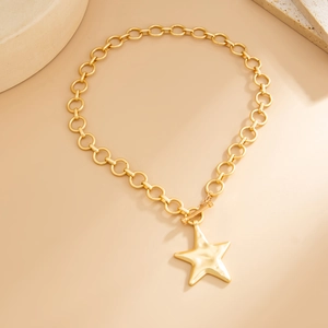 Detail of gold-tone star pendant necklace with toggle clasp on minimalist stone background