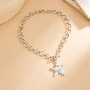 Detail of silver toggle clasp necklace with a polished star pendant on a beige surface
