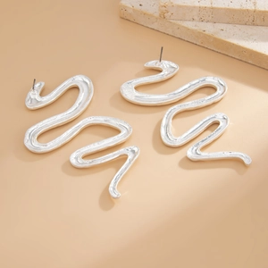 Dettaglio macro di orecchini a serpente in argento con superficie metallica strutturata