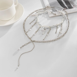 Dettaglio di collana a strati in argento con perle e pendente su una rivista di moda