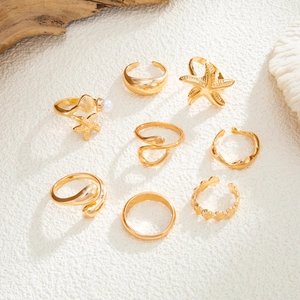 Detail of 8-piece gold jewelry set with starfish, seashell, pearls, and wavy textures