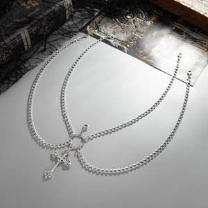 Close-up of a silver gothic layered body chain featuring an ornate cross pendant and metal rings