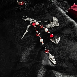 Gothic charm detail with silver bats, coffins and red heart beads on black fabric