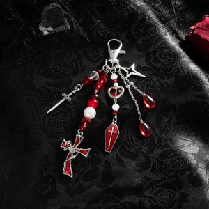 Gothic keychain detail with red coffin, silver sword, and cross on black lace