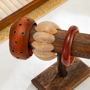 Dettaglio di bracciali con venature del legno e in resina marmorizzata su supporto in legno
