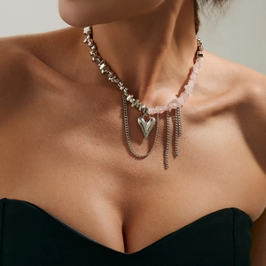 Dettaglio della collana con cuore, pietre rosa e nappe in metallo su una modella