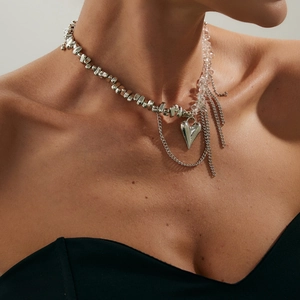 Primo piano della collana con ciondolo a cuore, perle irregolari e nappe metalliche