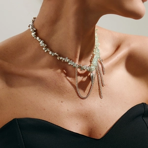 Dettaglio della collana con ciondolo a cuore, frange argentate e perline verdi su modella