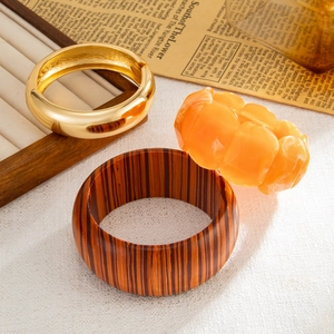 Dettaglio di bracciali in legno, metallo dorato e resina ambrata su uno sfondo vintage