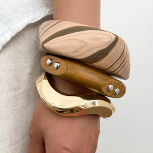 Bracciali geometrici impilati con texture in legno e design ondulato in metallo dorato