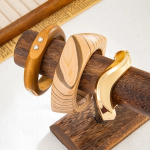Dettaglio di set bracciali in legno e metallo dorato ondulato su supporto scuro