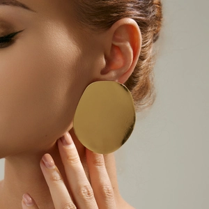 Nahaufnahme eines Models mit goldenen unregelmäßigen Diskus-Ohrringen in Hochglanzoptik