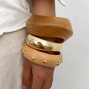 Detailed close-up of a three-piece chunky bracelet set with wood and gold metal textures