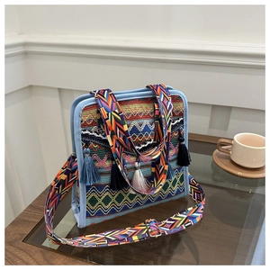 Dettaglio macro della borsa a secchiello boho con motivi geometrici e nappe azzurre